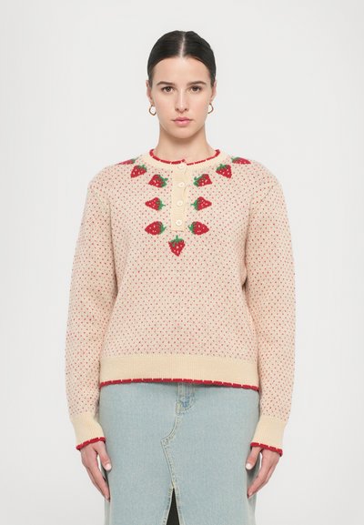 Beige gestrickter Pullover mit roten Erdbeerdesigns, Knopfverschluss am Hals und kontrastierenden roten Abschlüssen an den Bündchen und am Saum.