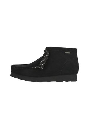 Black suede ankle boot with a rounded toe, unique braided lacing detail, and a textured rubber sole for grip. Waterproof Gore-Tex material.