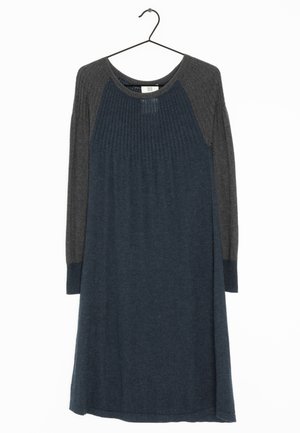 Robe en maille longueur genou avec corps bleu foncé et manches raglan longues gris charbon sur un cintre noir contre un fond blanc.