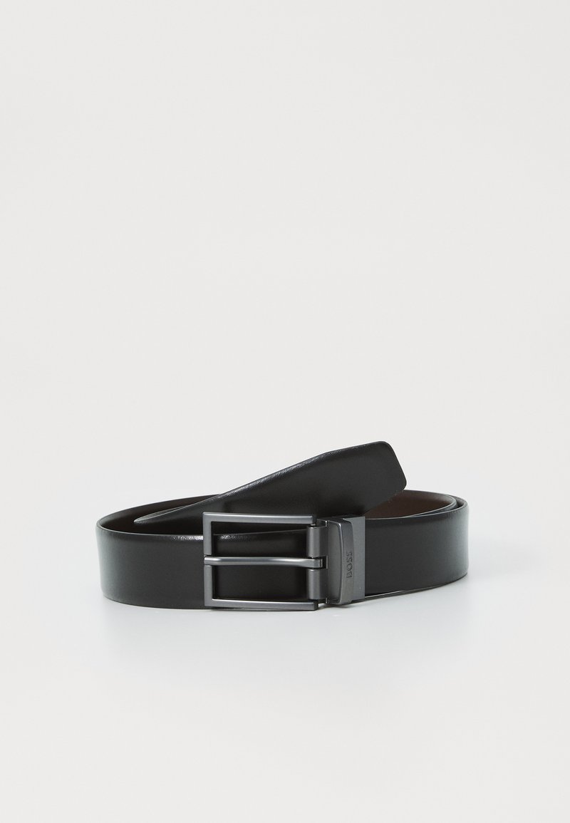 Črn usnjen pas z gladko površino, opremljen s pravokotno kovinsko sponko v mat črni barvi in minimalističnim dizajnom.