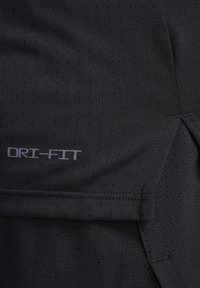 Schwarzes Sportshirt mit Dri-Fit-Technologie, strukturiertem Stoff mit kleinen Perforationen und flachen Nähten für Komfort und Atmungsaktivität.