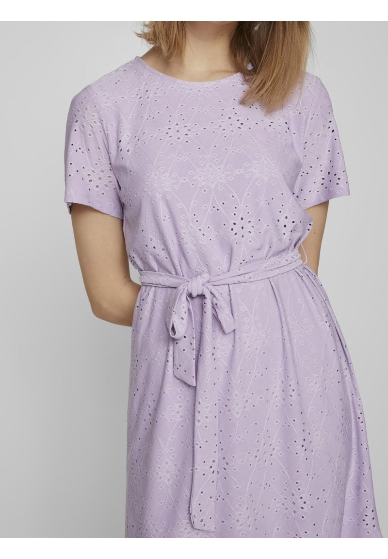 Lavender short-sleeved dress with eyelet detailing and a tied waist. Soft fabric, relaxed fit, and floral patterns throughout.