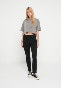 Γκρι κοντομάνικο κοντό T-shirt, συνδυασμένο με μαύρα τζιν κανονική γραμμή και μαύρα αθλητικά παπούτσια. Ύφασμα επίπεδο, με υφή, μίνιμαλ σχεδιασμός.