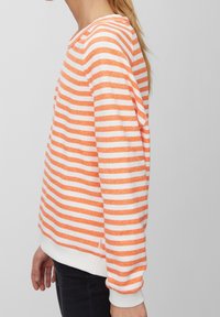 Oranssi-valkoraidallinen collegepaita, kevyt kangas, pyöreä pääntie, resorit hihansuissa ja helmassa, rento istuvuus ja sivuhalkiot.