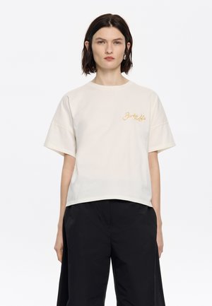 T-shirt in cotone color crema con maniche corte e vestibilità rilassata, con ricamo in oro sulla parte sinistra del petto.