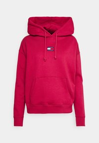 Červená mikina s kapucí vyrobená z měkké tkaniny, s klokankou, žebrovanými manžetami a malým logem "Tommy Jeans" na hrudi.