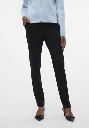 Černé kalhoty slim fit vyrobené z měkkého materiálu, doplněné o černé lodičky s špičatou špičkou a akcentem ve tvaru mašle. Světle modrá zipová mikina.