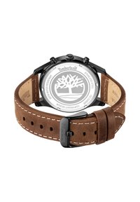 Orologio rotondo in acciaio inox nero con cinturino in pelle scamosciata marrone, cuciture bianche e logo inciso sulla fibbia. Design resistente all'acqua.