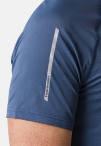 Blaues Sportshirt aus strukturiertem, atmungsaktivem Stoff. Mit einem reflektierenden silbernen Akzent auf der Schulter und dem Markennamen "Swedemount."