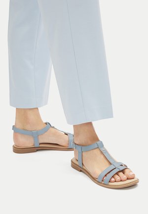 Jasnoniebieskie sandały na płaskiej podeszwie z regulowanymi paskami wokół kostki, o fakturowanym wykończeniu i metalowych akcentach.