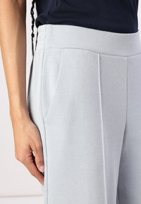 Γαλάζιο υφασμάτινο παντελόνι με φαρδύ λάστιχο και πλαϊνές τσέπες, με σχεδίαση ίσιων ποδιών και ορατές ραφές.