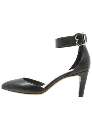 Chaussure à talon haut en cuir noir à bout pointu, avec bride à la cheville et boucle argentée, talon fin de hauteur moyenne, vue de profil.