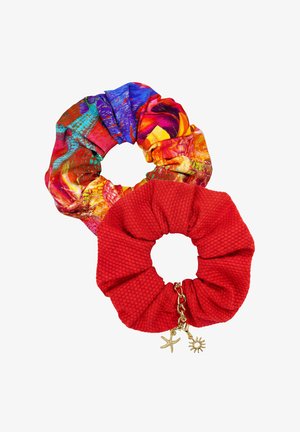 Dwa materiałowe gumki do włosów, jedna w wielokolorowy abstrakcyjny wzór, druga czerwona z złotymi zawieszkami w kształcie rozgwiazdy i słońca.