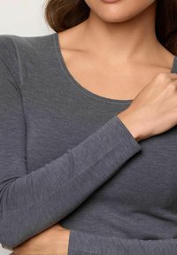 Maglietta grigia a maniche lunghe con scollatura a barca e texture morbida. Presenta un leggero gradiente di colore da grigio scuro a una tonalità più chiara.