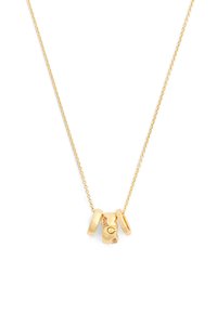 Collana con catena d'oro con tre pendenti d'oro, incluso un ciondolo a forma di orso con piccoli cristalli e la parola "COACH" incisa su un anello.