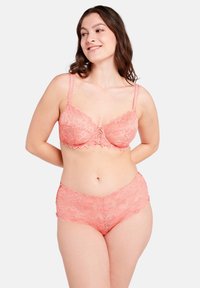 Set di lingerie in pizzo color rosa pastello, con motivi floreali, texture morbida e bordi ondulati. Include un reggiseno con spalline regolabili e slip coordinati.