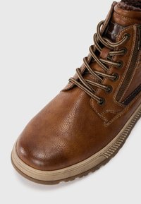 Braune Leder-Ankle Boots mit runder Zehenpartie, texturierter Oberfläche, kontrastierenden Schnürsenkeln, seitlichem Reißverschluss und beigefarbenem Gummisohle.