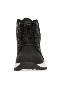 Botte de randonnée noire en matériau synthétique, avec des lacets robustes, des œillets en métal et une semelle en caoutchouc blanche. Surface texturée avec un design robuste.