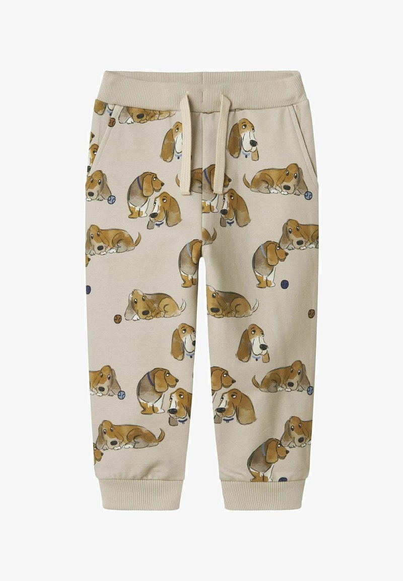 Beige Jogginghose mit einem wiederholten Druck von Basset Hunden in verschiedenen Posen. Material: weicher Stoff; elastischer Bund und Bündchen.