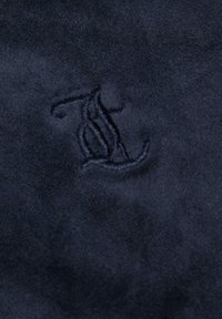 Tessuto in suede blu navy con una consistenza morbida, caratterizzato da un monogramma ricamato in un filo di un tono leggermente più scuro per creare un contrasto visivo.