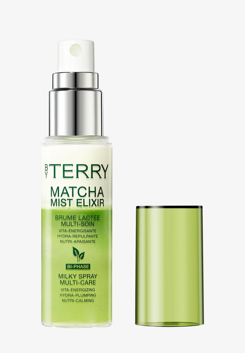 Flacon spray en verre transparent avec un liquide blanc et vert étiqueté By Terry Matcha Mist Elixir, avec un bouchon vert translucide à côté.