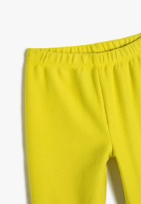 Helle gelbe Leggings mit geripptem Muster und elastischem Bund, gestaltet für Komfort und einfache Handhabung.