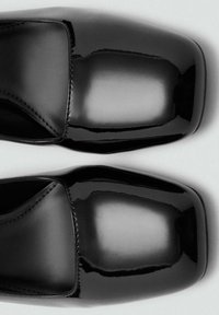 Czarne lakierowane buty ze skóry z kwadratowym noskiem, gładką powierzchnią, minimalnym przeszyciem i wysokim połyskiem.
