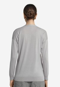Ljusgrå långärmad tröja, ribbat halsringning och mudd, mjuk textur, rak fåll och sänka axlar. Minimalistisk design.
