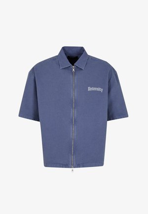 Veste en denim à manches courtes bleue, avec fermeture éclair, col pointu et logo "Reternity" en blanc sur le côté gauche.