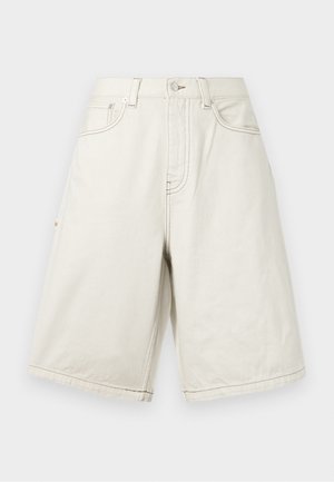 Μπεζ σορτς από τζιν με χαλαρή γραμμή, διαθέτουν θηλιές για ζώνη, μπροστινές τσέπες και ορατή ραφή. Το ύφασμα έχει απαλή υφή.