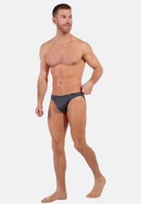 Herren Badebriefe in Grau, aus glattem Material mit minimalistischem Design. Niedrig geschnitten und mit einem dezenten Logo am Bund.