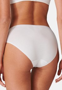Weiße Baumwollslips mit glatter Textur, hochgeschnittenem Design und elastischem Bund. Verfügt über minimale Nähte für ein nahtloses Finish.