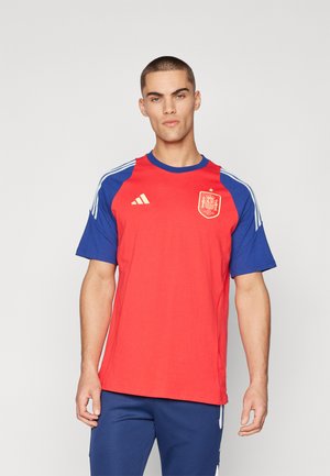 Red short-sleeve football shirt with blue sleeves, featuring a gold emblem and three white stripes on each shoulder.
