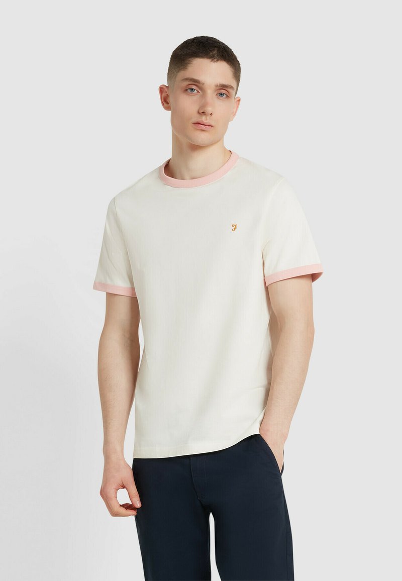 T-shirt in cotone con corpo crema e colletto e maniche a coste rosa chiaro. Presenta un piccolo logo arancione sul petto. Maniche corte.