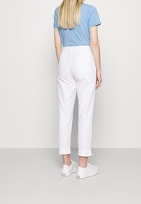 Vita bomullsbyxor med en lätt avsmalning, med uppvikta fållar och hög midja. Parat med vita sneakers med en enkel design.