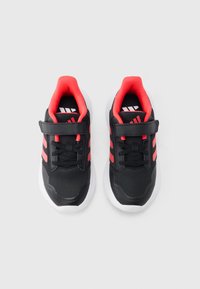 Czarno-czerwone buty sportowe z siateczkową cholewką, zaokrąglonym noskiem, gumową podeszwą i paskiem na rzep, z trzema paskami po każdej stronie.
