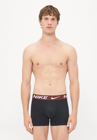Crni Nike bokserice s bordo pojasom s bijelim logotipom; tijesnim dizajnom s glatkom teksturom i bez vidljivih uzoraka.