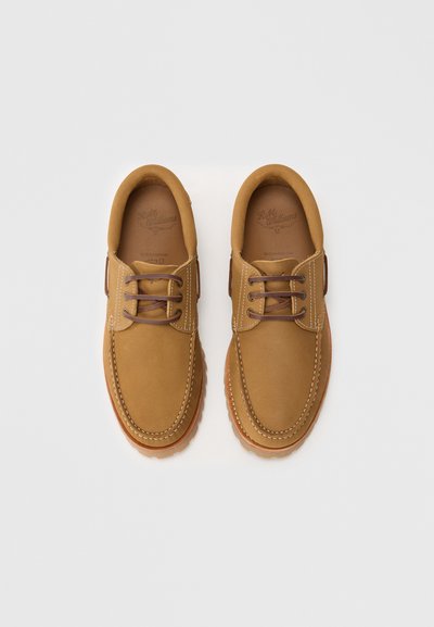 Scarpe in pelle marrone con punta arrotondata, cuciture a contrasto e lacci marroni. La suola è texturizzata con un leggero dettaglio a piattaforma.