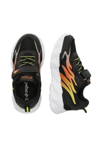 Baskets de sport noires avec motifs de flammes orange et jaunes, une tige en mesh, une semelle blanche et une sangle ajustable pour un maintien sécurisé.