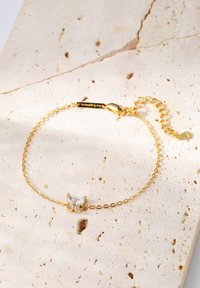 Gold chain bracelet featuring a butterfly design with clear gemstones at the center. Adjustable clasp with a delicate link chain.