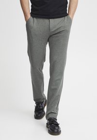 Pantalones deportivos en gris, ajustados y con una textura suave, que cuentan con bolsillos laterales y un ajuste cómodo, combinados con zapatos negros de cordones.