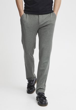 Pantalones deportivos en gris, ajustados y con una textura suave, que cuentan con bolsillos laterales y un ajuste cómodo, combinados con zapatos negros de cordones.