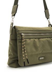 Borsa imbottita verde oliva con tasca frontale con zip, caratterizzata da un dettaglio in corda e accessori in argento. Inclusa una tracolla regolabile.
