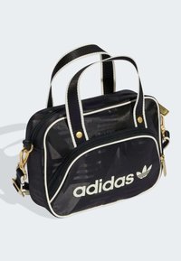 Czarna nylonowa torba z białymi akcentami, zamkiem błyskawicznym, krótką rączką, regulowanym paskiem, złotym okuciem i nadrukowanym logo z przodu.