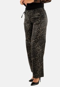 Pantalones de estampado de leopardo hechos de un tejido texturizado, con corte recto, bolsillos laterales y un detalle de lazo en la cintura. Incluye tacones altos negros.