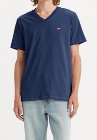 Marineblå bomulds t-shirt med v-hals og korte ærmer; har et lille rødt Levi's logo på brystet; glat tekstur.