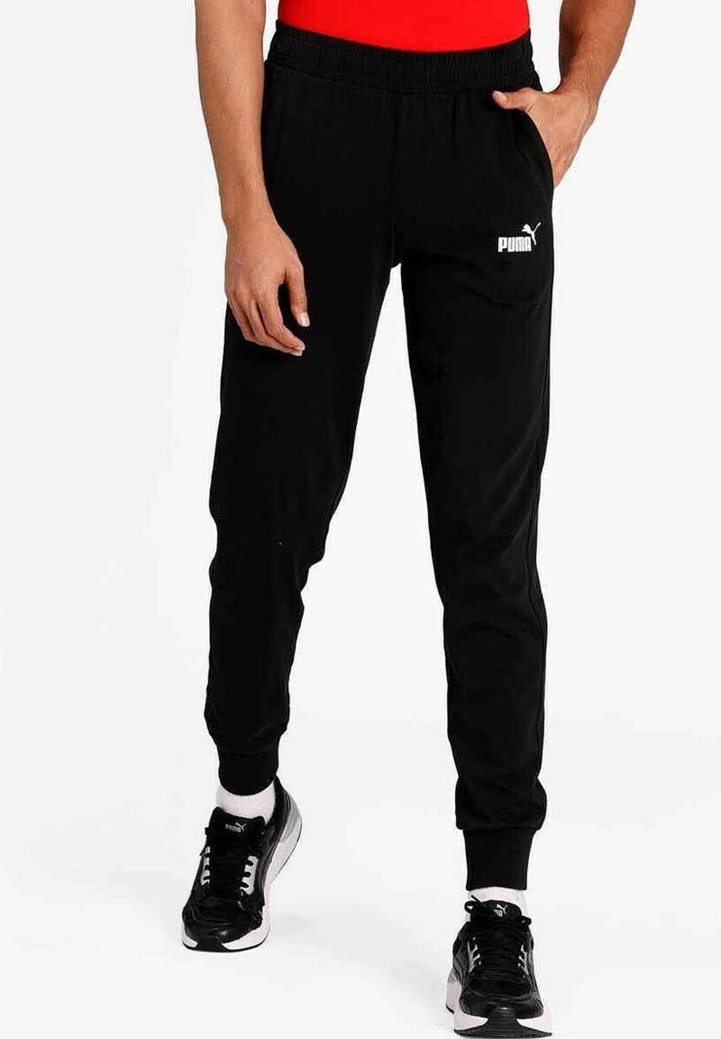 Pantaloni sportivi neri con elastico in vita, caviglie a costine e un logo Puma bianco sulla coscia sinistra, realizzati in materiale morbido e traspirante.