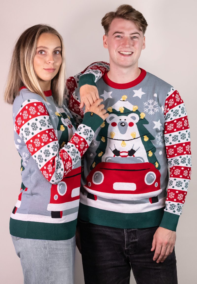 Rote und graue Feiertagspullover mit einem Eisbären in einem Weihnachtsbaum, dekoriert mit Schneeflocken und Lichtern. Grüne Rippstrickbündchen und Saum.