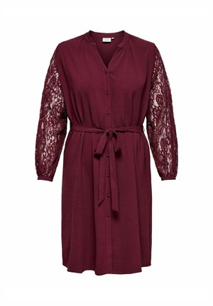 Gravidkjole i burgunder med teksturert kropp, blonde ermer med knapp foran og knytebelte i midjen. Har en avslappet passform.