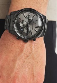 Montre chronographe en acier inoxydable noir avec un cadran gris, une lunette texturée et trois sous-cadrans ; chiffre arabe "XII" en haut.